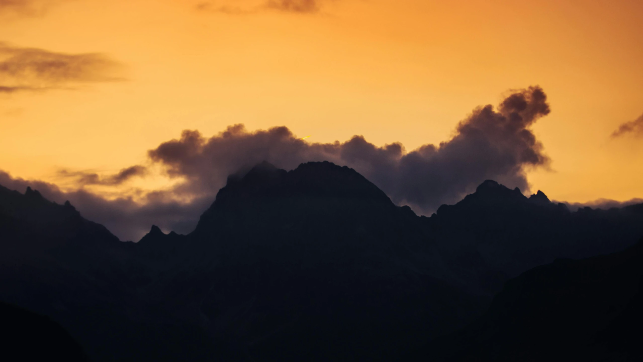 a large group of clouds coming off a mountain top