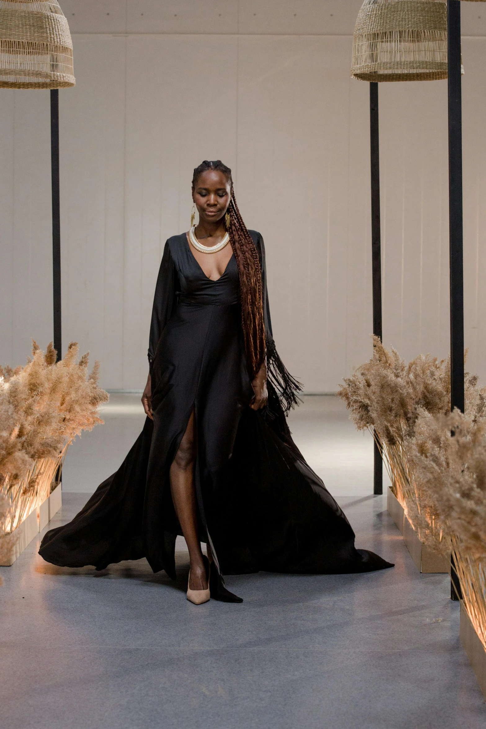 a woman walking down a runway in a black dress