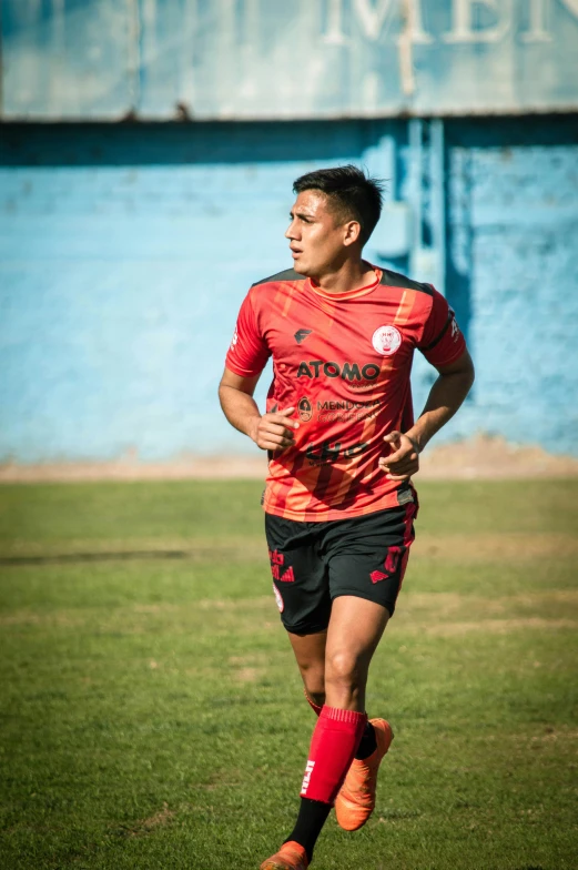 a man in a red soccer uniform on a field