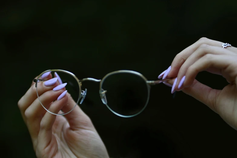 a woman with pink nails holding on to a pair of glasses