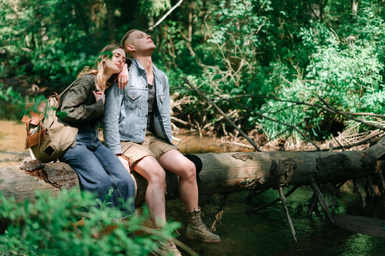 two people are sitting on a fallen down tree trunk