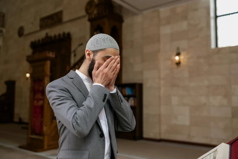 a man wearing a suit and praying in a building