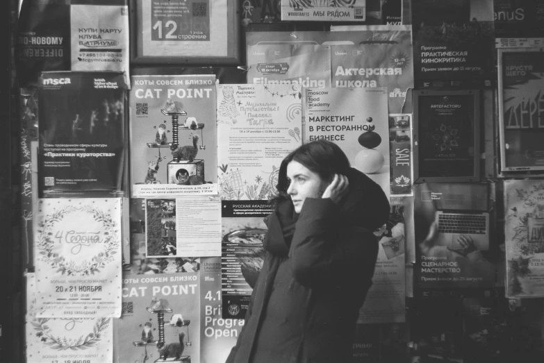 a woman talks on her cell phone in front of a wall of news