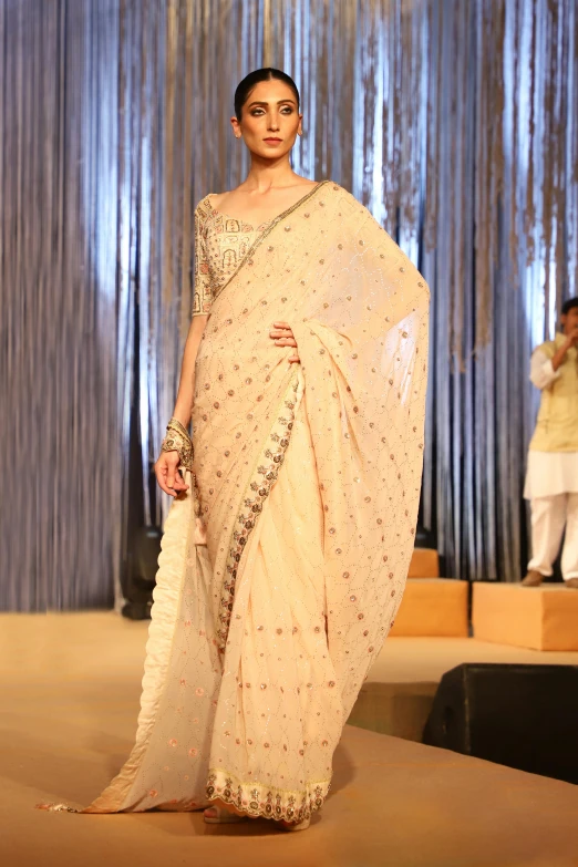 a model in an embroidered, off white saree