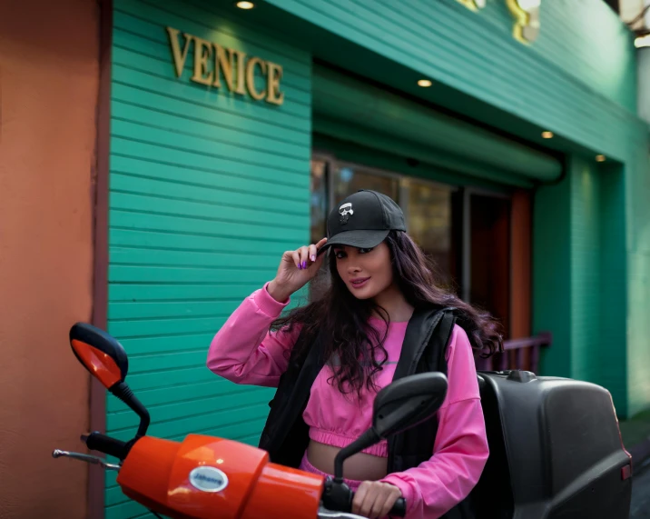 a lady with a pink top on standing near a motorcycle