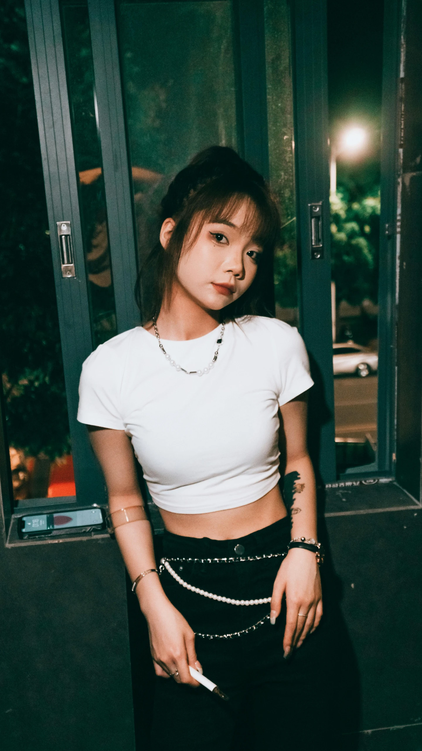 a girl with long dark hair in white shirt holding cigarette