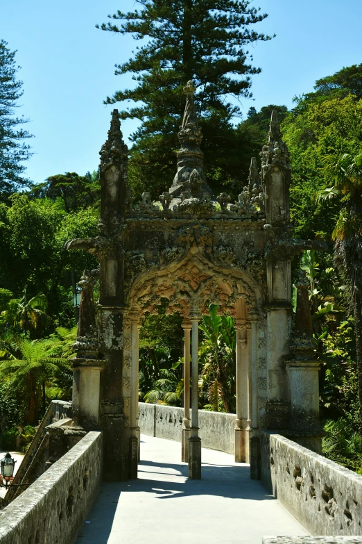 an ancient looking arch next to the woods