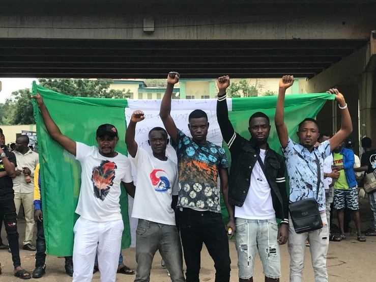 men holding green flag on their shoulders with their hands up