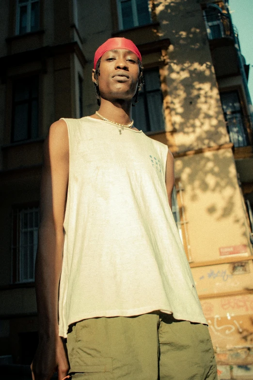 a young man in a white top is standing on a street