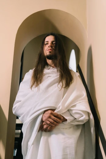 the man with long hair and wearing a white robe
