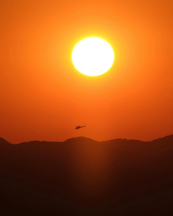 the sun rises over mountains with silhouettes of an airplane