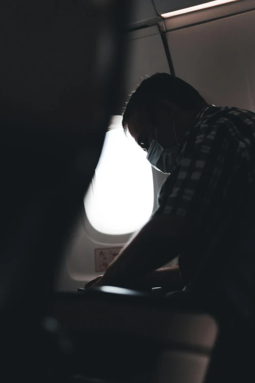 a man standing next to an airplane window in the dark