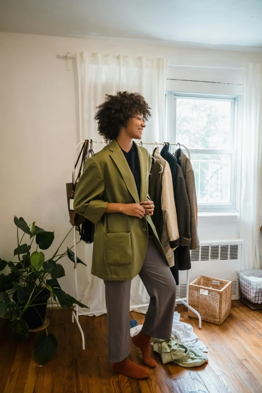 a woman with curly hair is standing by some clothes