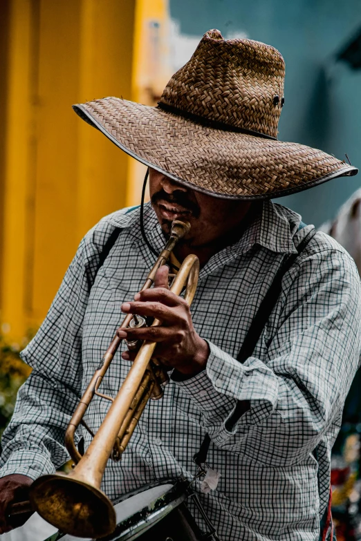 a man wearing a brown cowboy hat playing a trumpet