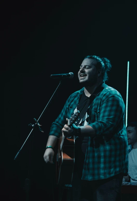 a man holding a guitar in front of a microphone