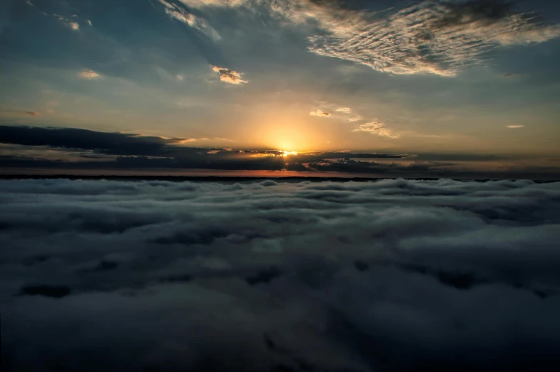 the sun is setting over the clouds at the ocean