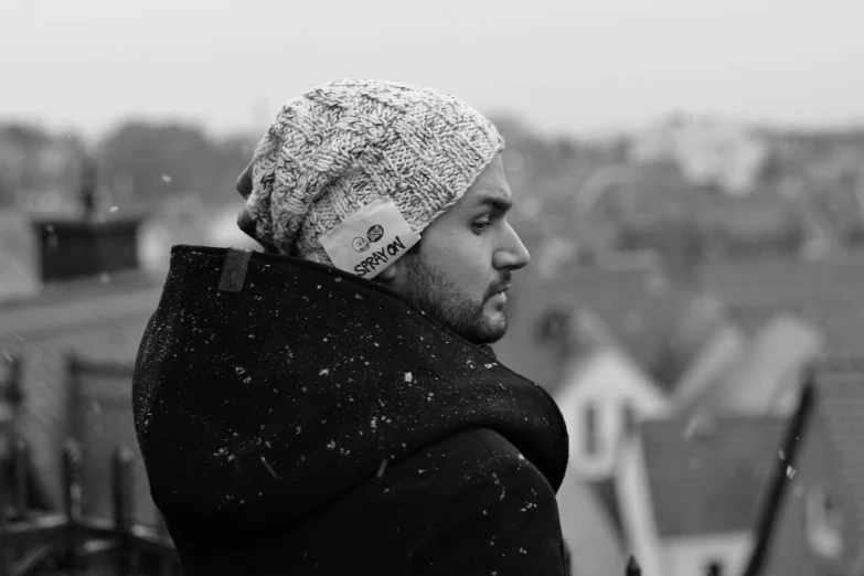 a man wearing a beanie standing in front of the city