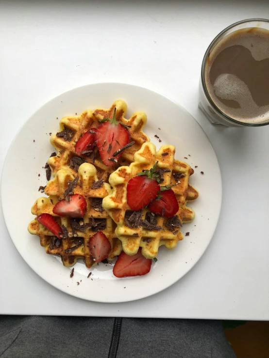 a white plate topped with waffles covered in berries and chocolate