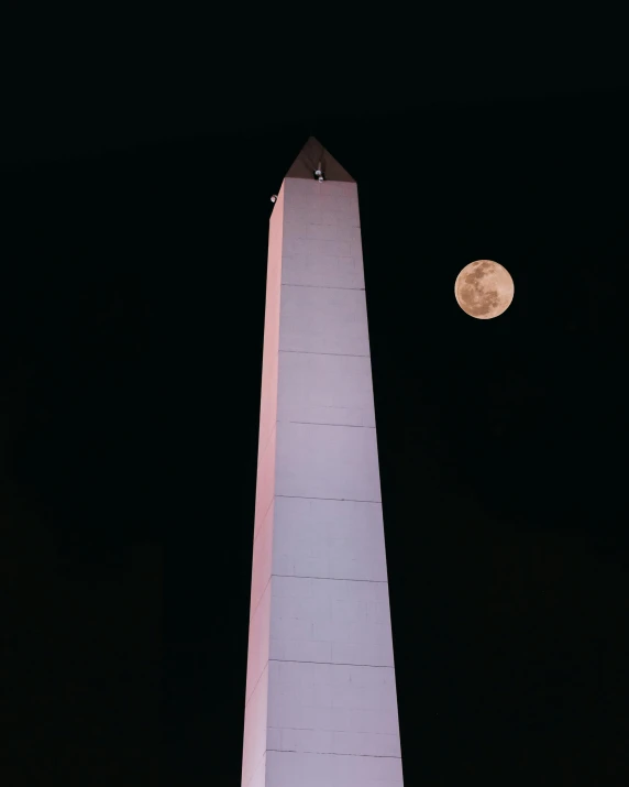 the moon rises over the washington monument at night