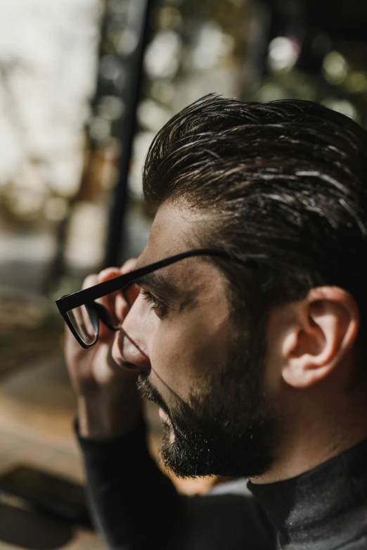 a man with a beard and glasses talking on a cell phone