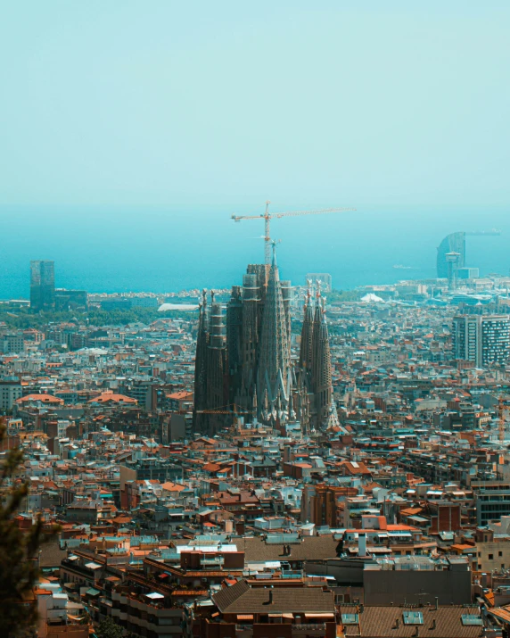 the barcelona skyline and its many towers as seen from the top of a mountain