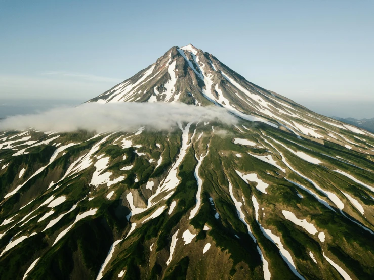 the top of a snow capped mountain covered in cloud