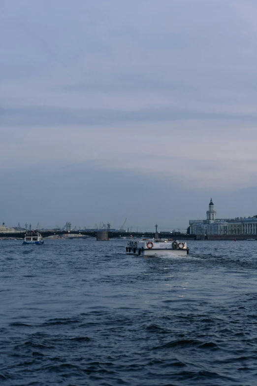 boats floating down the water by a big building