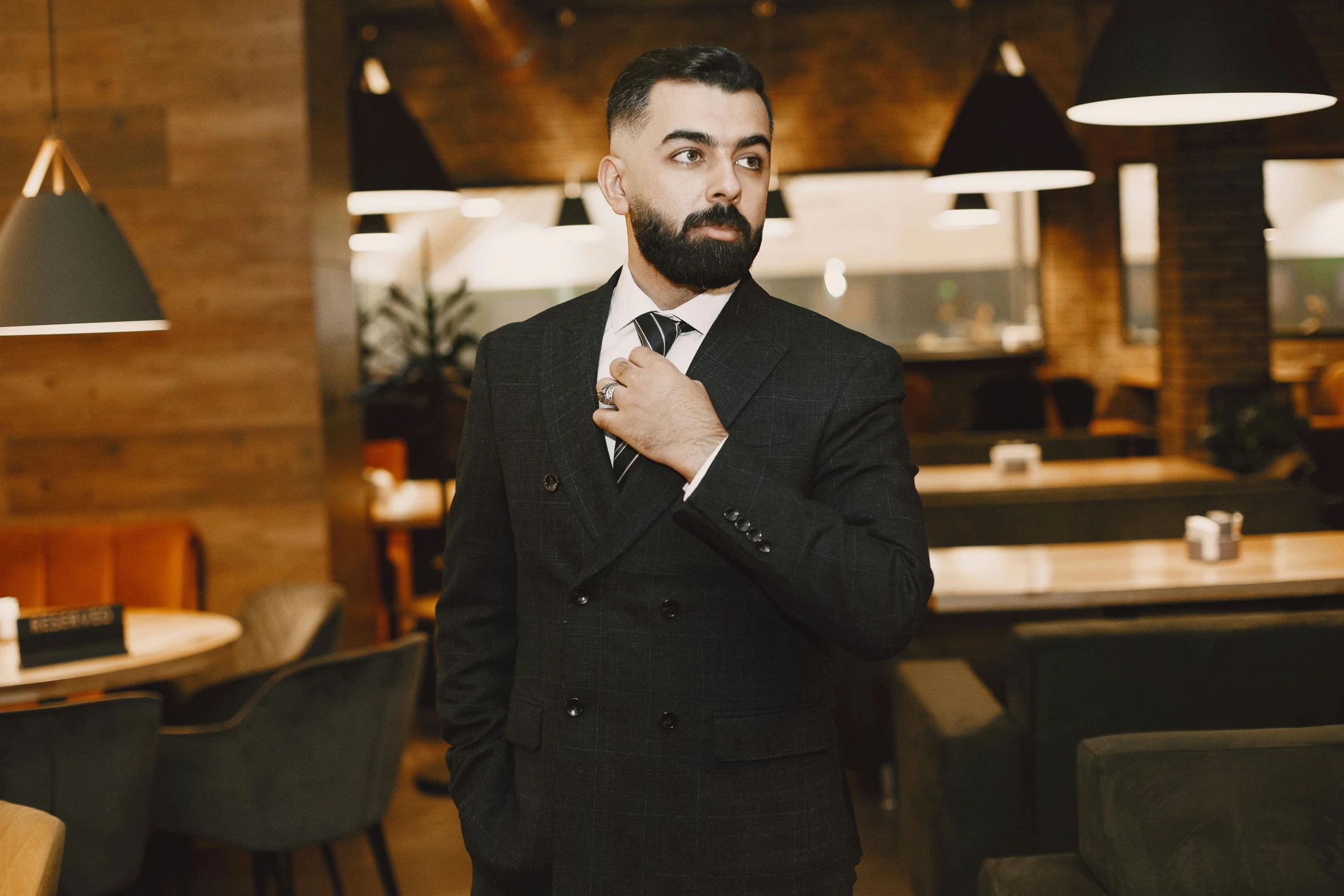 a man wearing a suit adjusting his tie in a restaurant