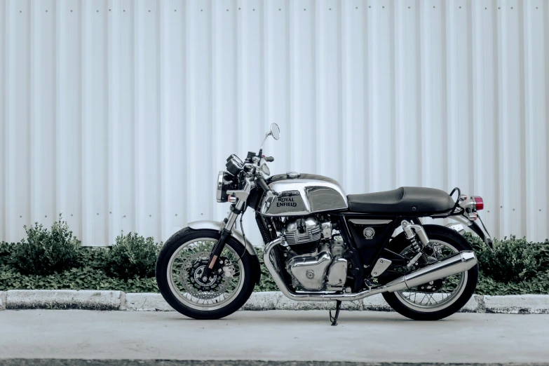 black and silver motorcycle sitting parked on cement next to wall