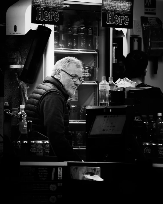 a man wearing a vest is writing on the counter