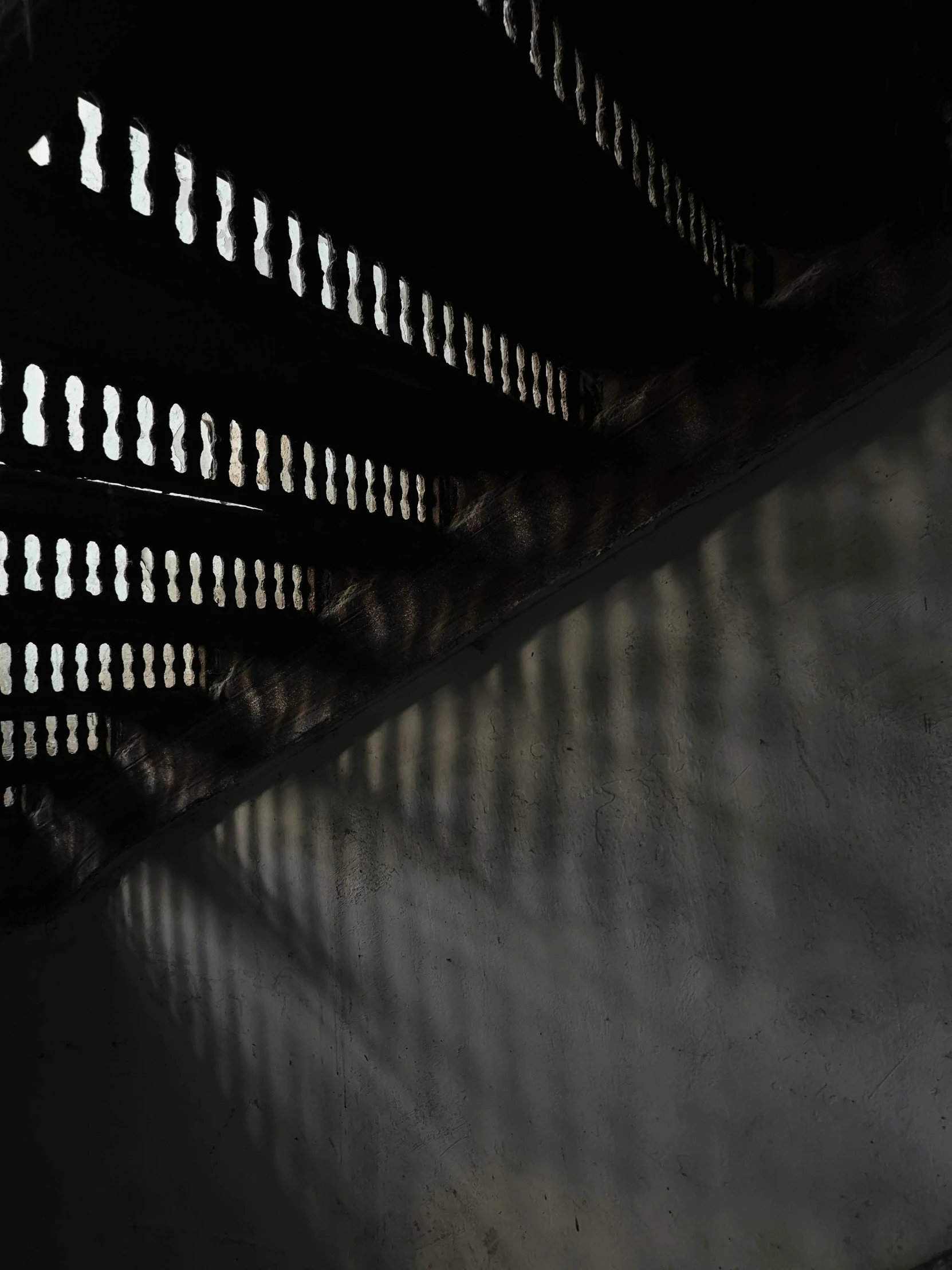 shadows cast on wall by street light with bench in foreground