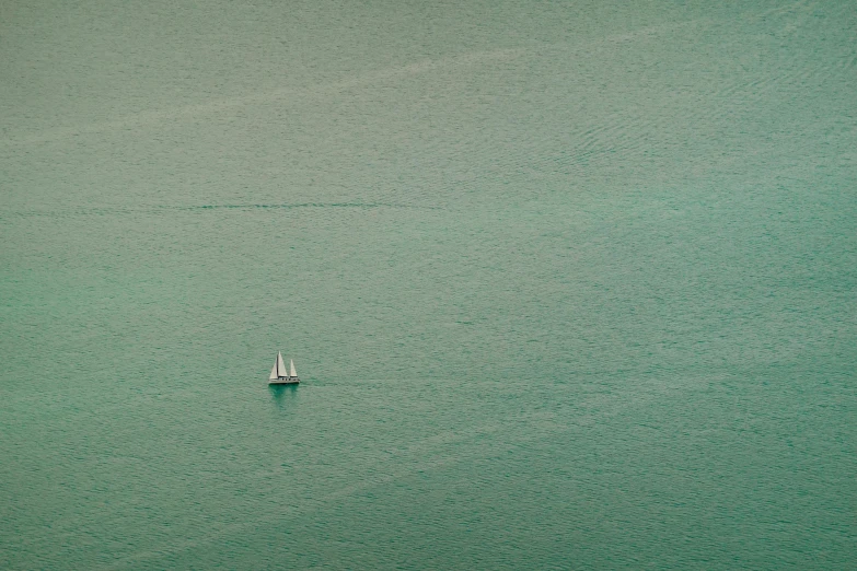 a lone sailboat in the middle of a body of water