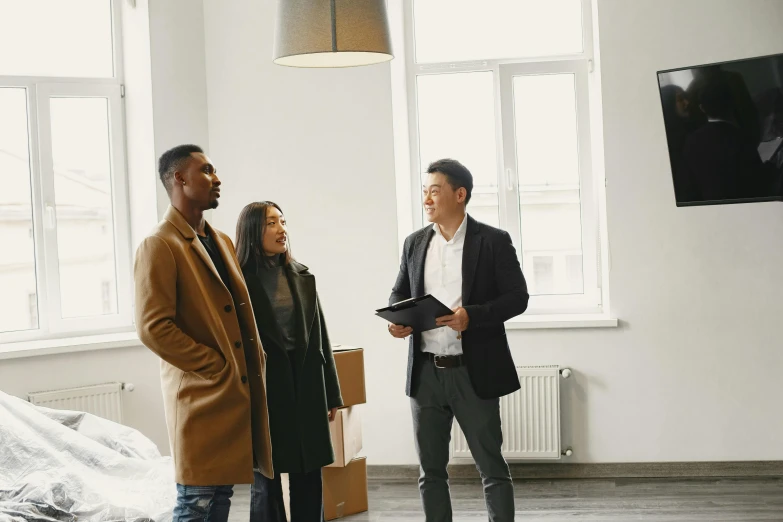 two men and a woman standing in an empty apartment