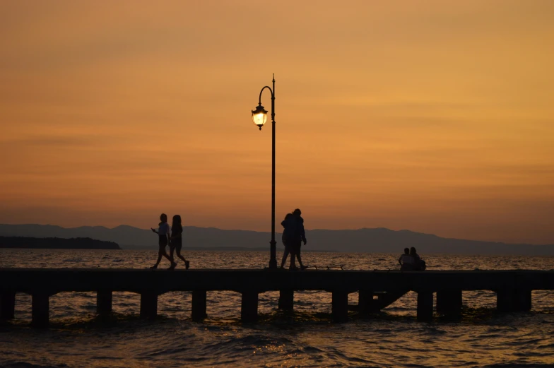 three people standing near the water at sunset