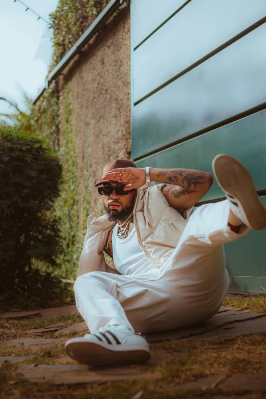 a man sitting on the ground wearing white pants and a shirt