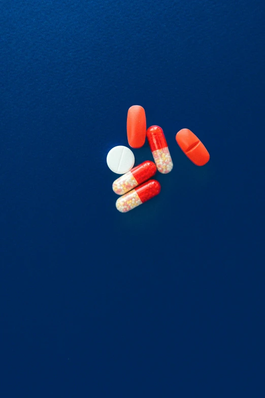 two orange and one white pills are laying on a blue surface