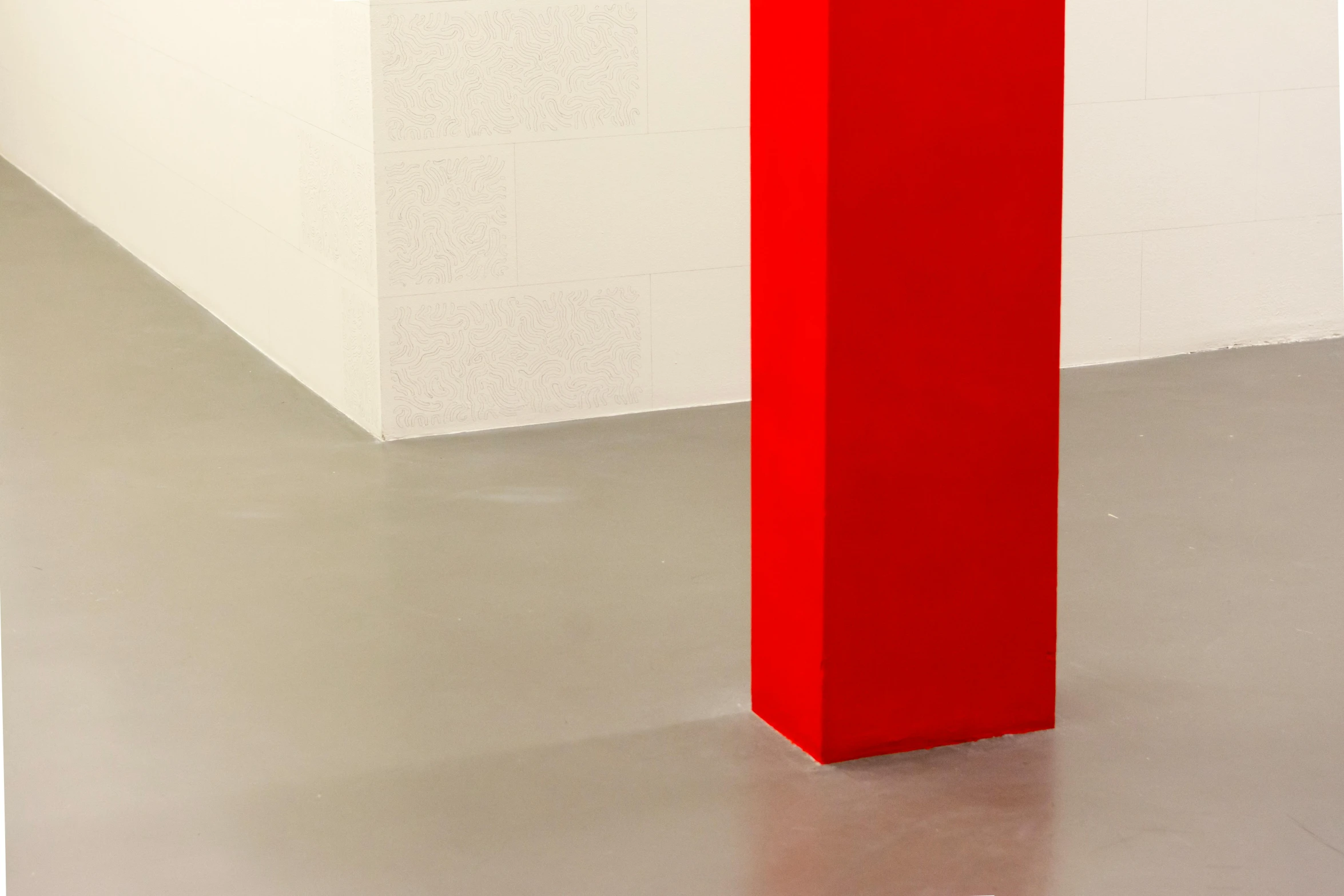 a tall red object on a silver surface next to a brick wall