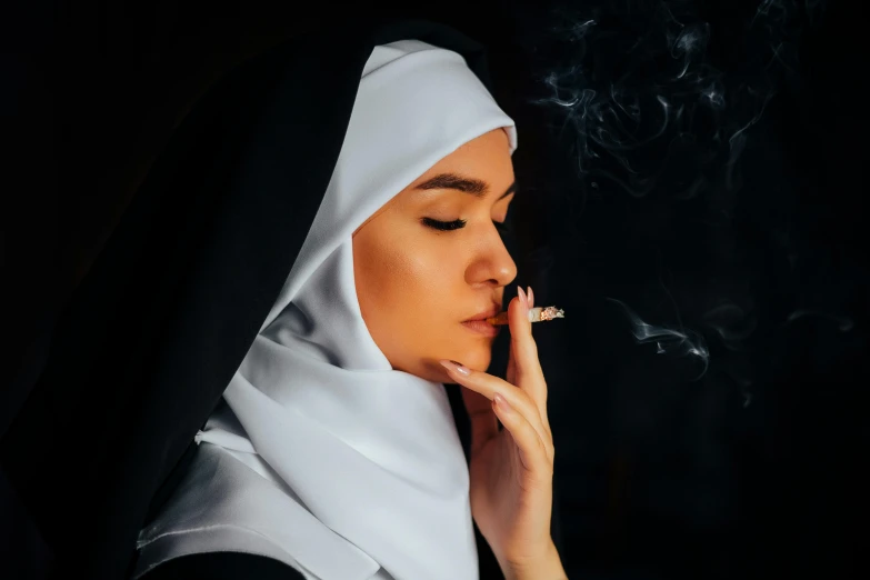 a nun smoking a cigarette with her head wrapped in black
