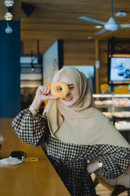 a woman in hijab holding a doughnut
