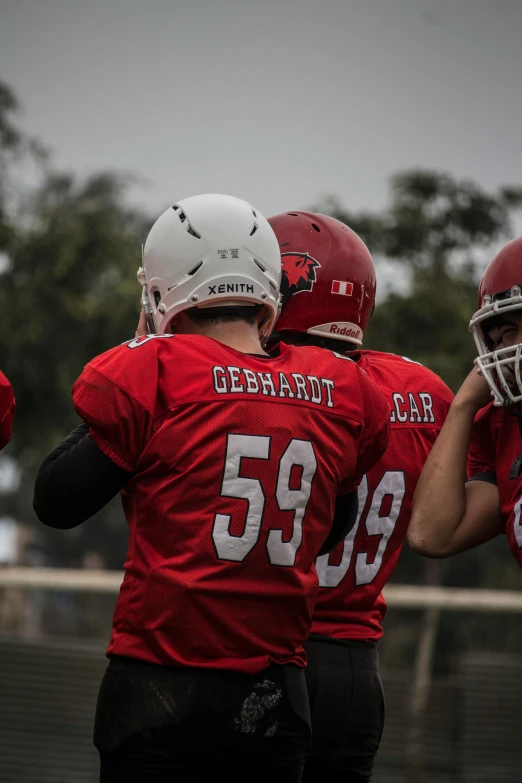 three children on football team facing off against a gray sky