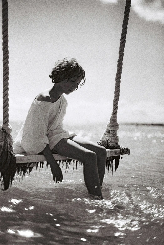 the little girl sitting on the swing is wearing a white shirt