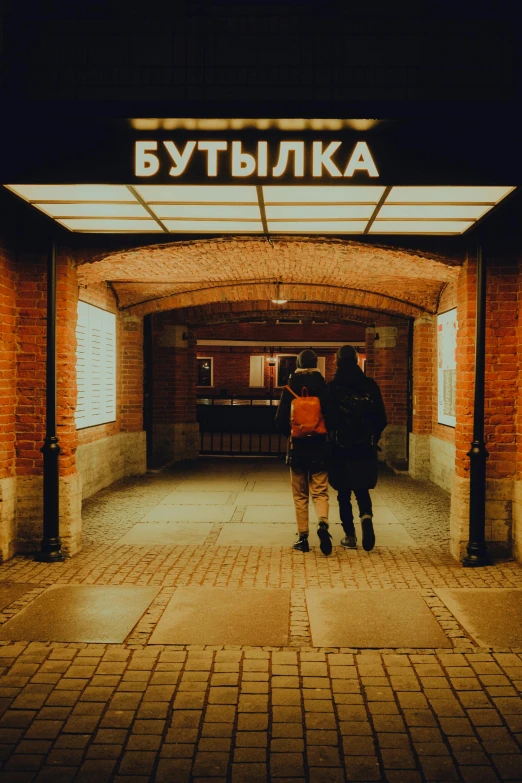 two people standing outside of a brick building