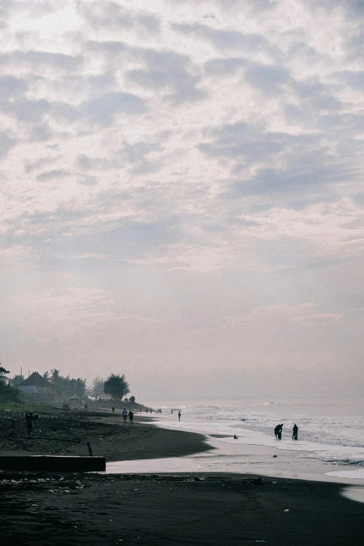 people at the beach during low tide on an overcast day