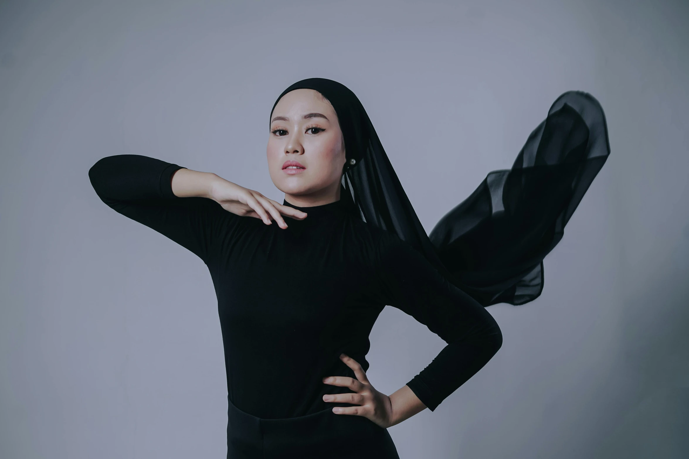 a woman is posing in black with her arm on her head