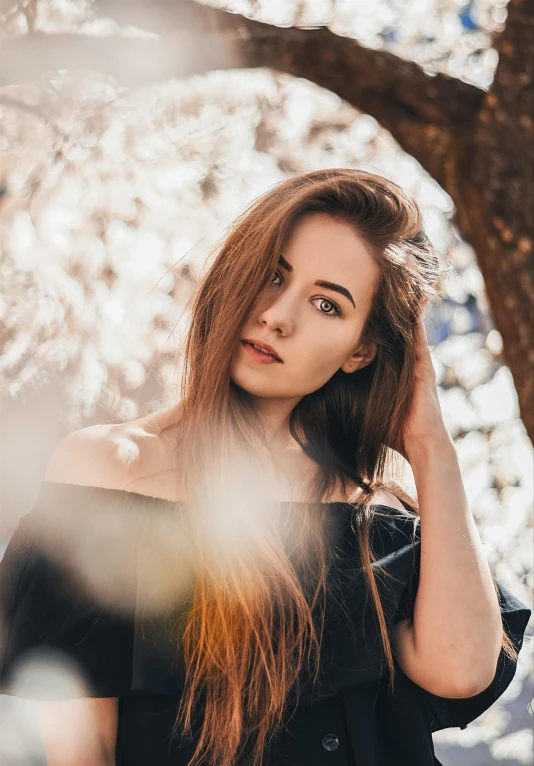 the young woman is posing under a tree