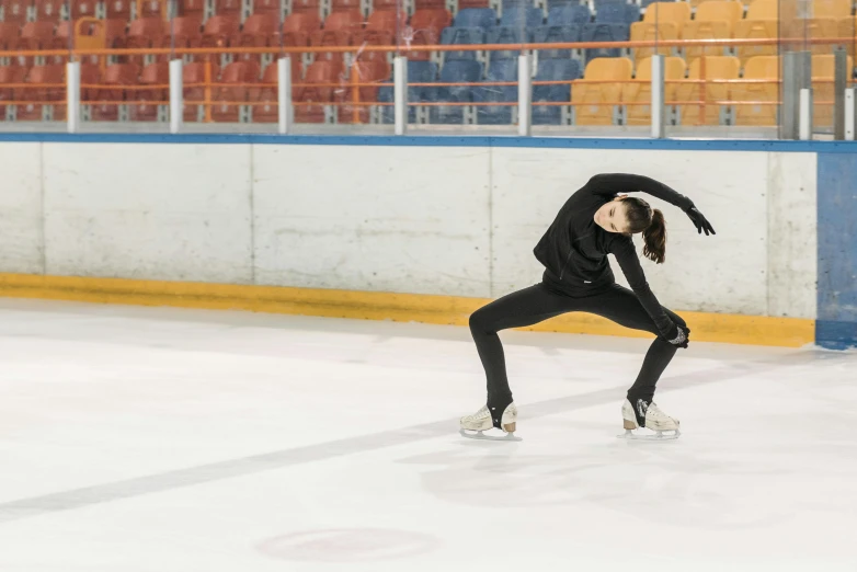 a woman skating on an ice rink with her arms in the air