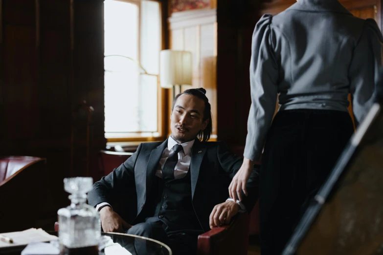 a man sitting in an old chair next to another man