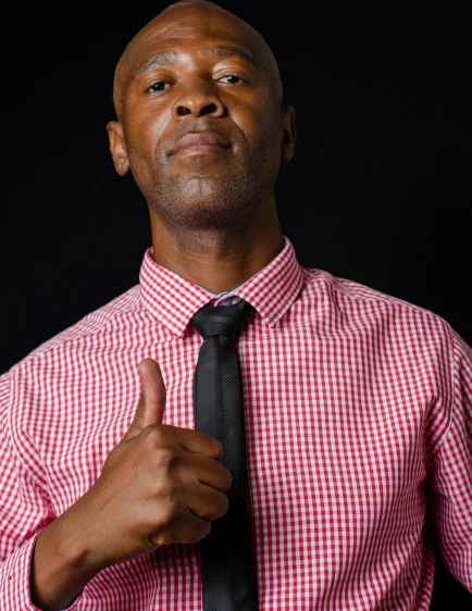 the man poses for the camera while wearing a checkered shirt and tie