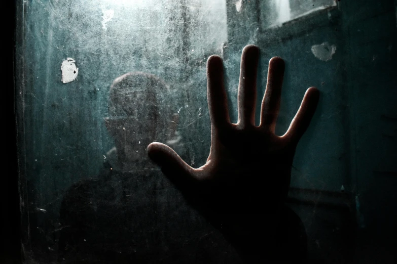 a hand reaching up toward the ground for someone behind a window