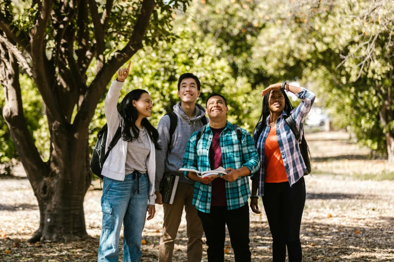 group of people standing under a tree, some waving